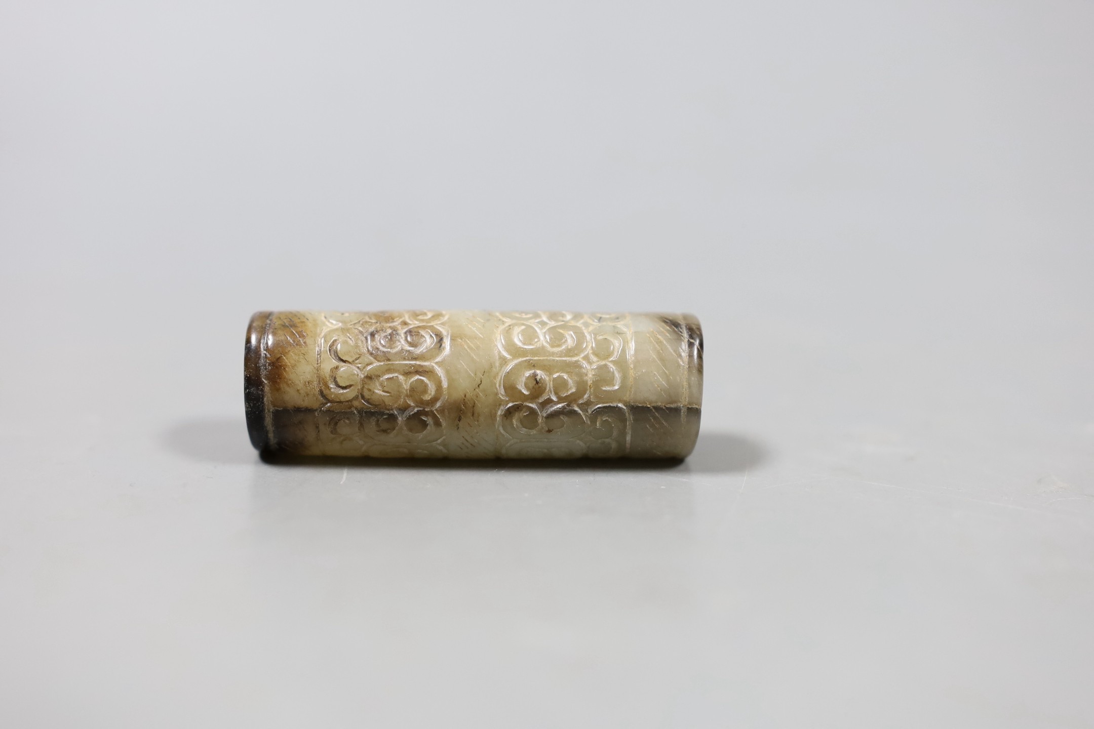 A Chinese archaistic white and black jade cylinder bead, 5.8 cm, boxed and a Chinese archaistic jade large bi disc, 13 cm diameter